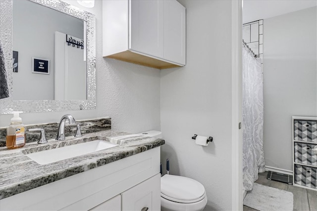 bathroom with toilet, vanity, and curtained shower