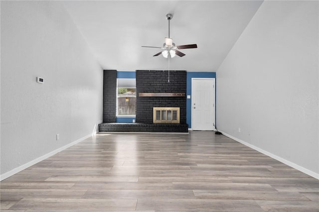 unfurnished living room with a brick fireplace, light hardwood / wood-style flooring, ceiling fan, and lofted ceiling