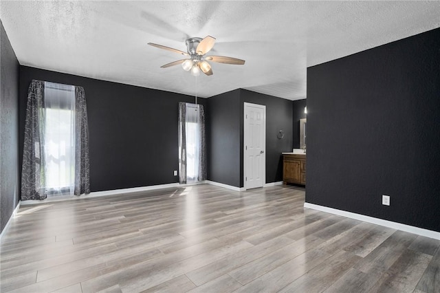 unfurnished living room with ceiling fan, a textured ceiling, and light hardwood / wood-style flooring