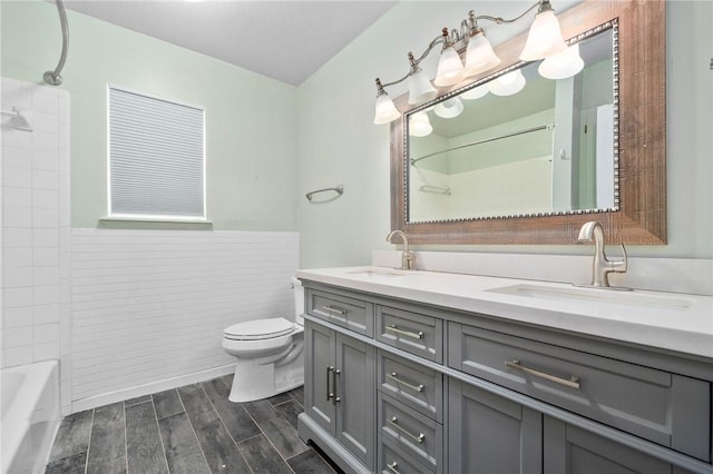 full bathroom with hardwood / wood-style floors, vanity, bathing tub / shower combination, toilet, and tile walls