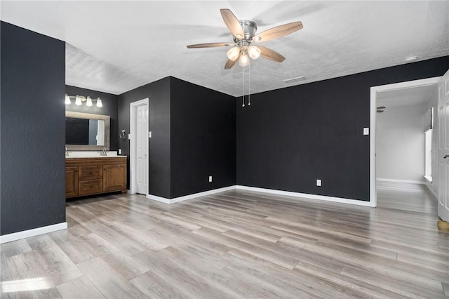 interior space with ensuite bath, ceiling fan, a textured ceiling, and light wood-type flooring