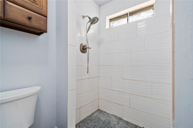 bathroom with a tile shower and toilet