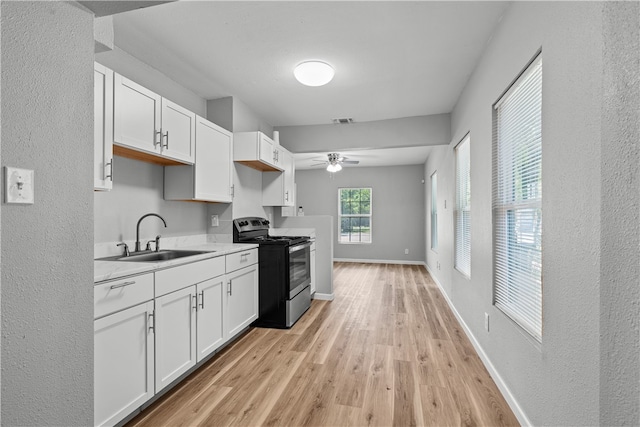 kitchen featuring sink, ceiling fan, light hardwood / wood-style flooring, white cabinets, and black / electric stove