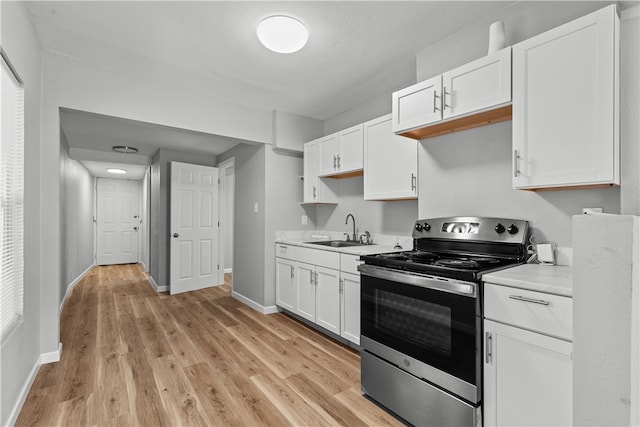 kitchen with white cabinets, light wood-type flooring, stainless steel electric range oven, and sink