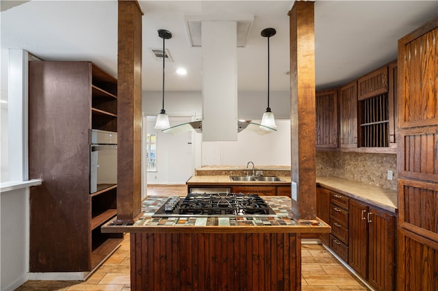 kitchen featuring gas cooktop, decorative backsplash, light wood-type flooring, sink, and a center island