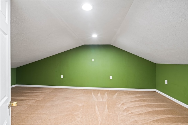 additional living space featuring lofted ceiling, carpet floors, and a textured ceiling