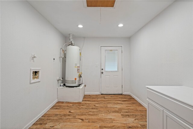 clothes washing area with water heater, light hardwood / wood-style flooring, washer hookup, and hookup for an electric dryer