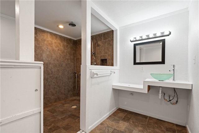 bathroom featuring a shower, sink, crown molding, and tile walls