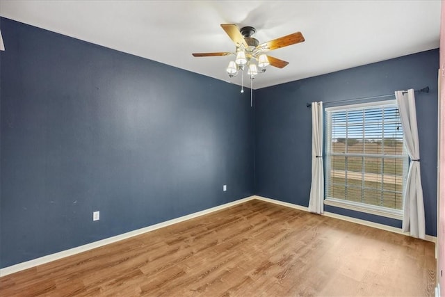 empty room with ceiling fan, baseboards, and wood finished floors