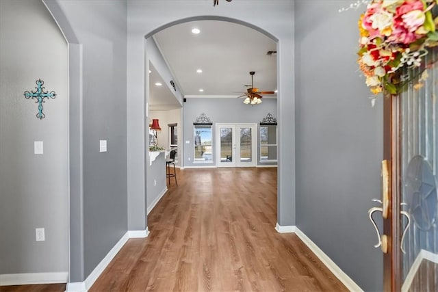 entrance foyer with arched walkways, french doors, a ceiling fan, wood finished floors, and baseboards