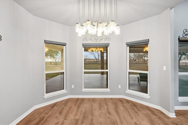 unfurnished dining area featuring wood finished floors and baseboards