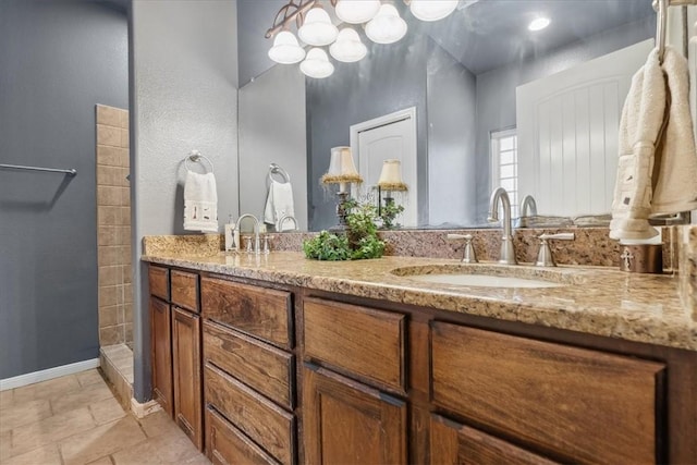 full bathroom with a sink, a tile shower, baseboards, and double vanity