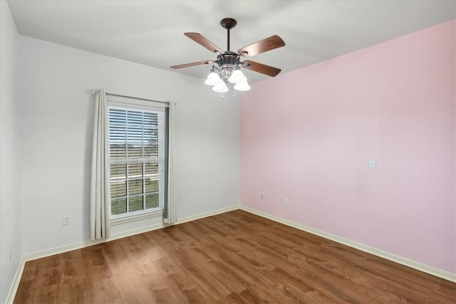 empty room featuring ceiling fan, baseboards, and wood finished floors