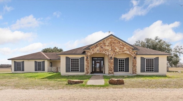 ranch-style home with a front yard and stone siding