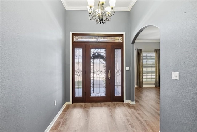 entrance foyer featuring arched walkways, crown molding, baseboards, and wood finished floors