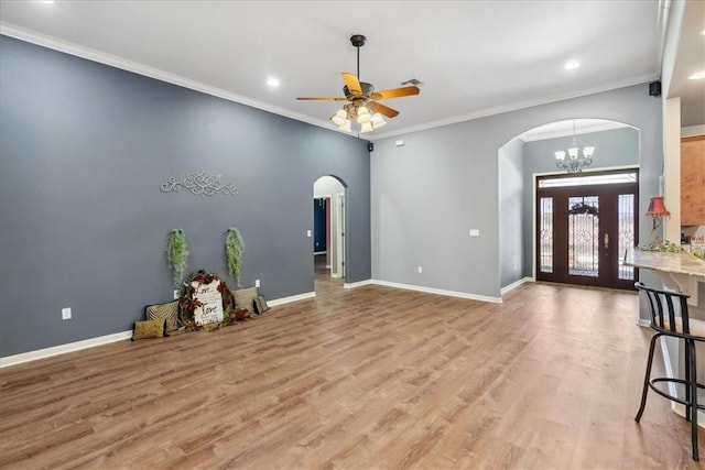 foyer entrance featuring arched walkways, crown molding, light wood finished floors, and baseboards