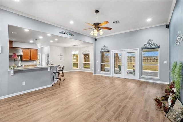 living area with recessed lighting, ornamental molding, a ceiling fan, light wood-type flooring, and baseboards