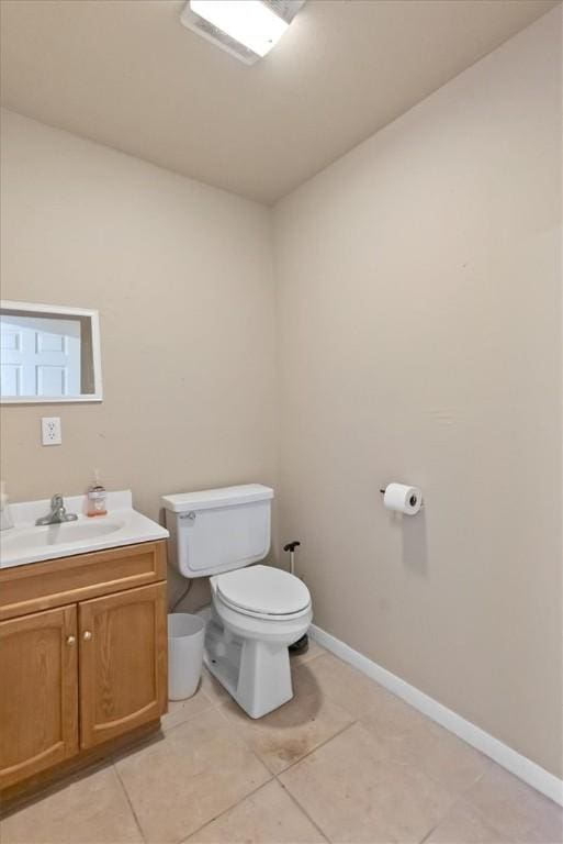 bathroom with toilet, tile patterned floors, baseboards, and vanity