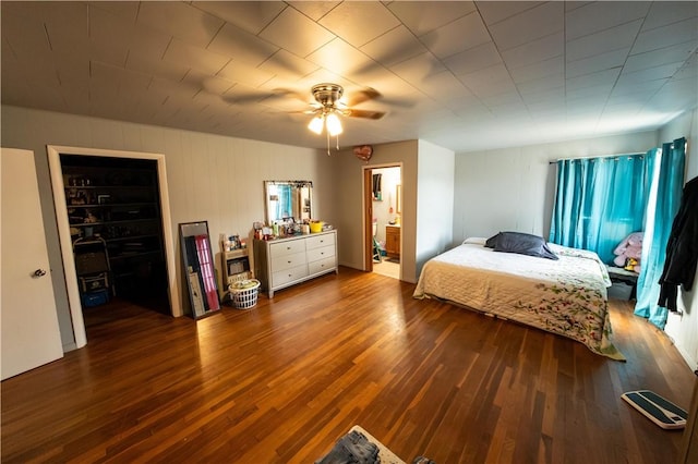 bedroom featuring a ceiling fan, wood finished floors, a walk in closet, and connected bathroom