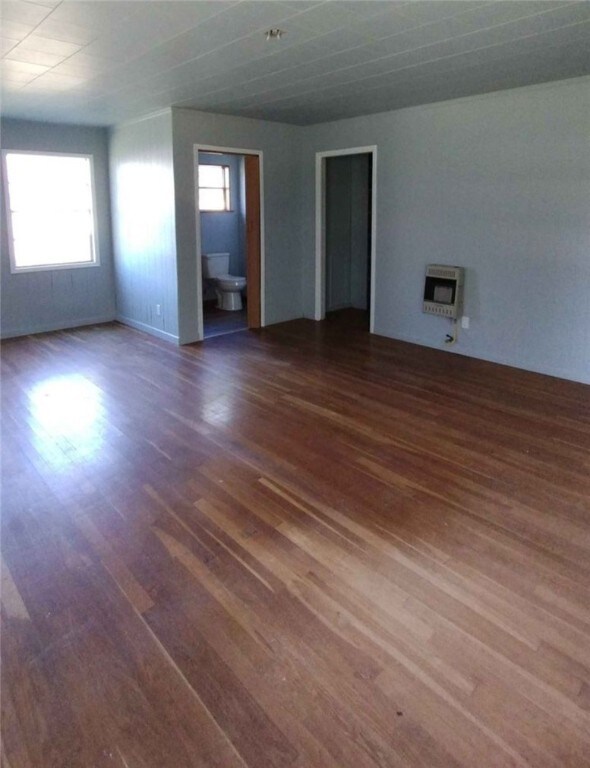 spare room with dark wood-type flooring and heating unit