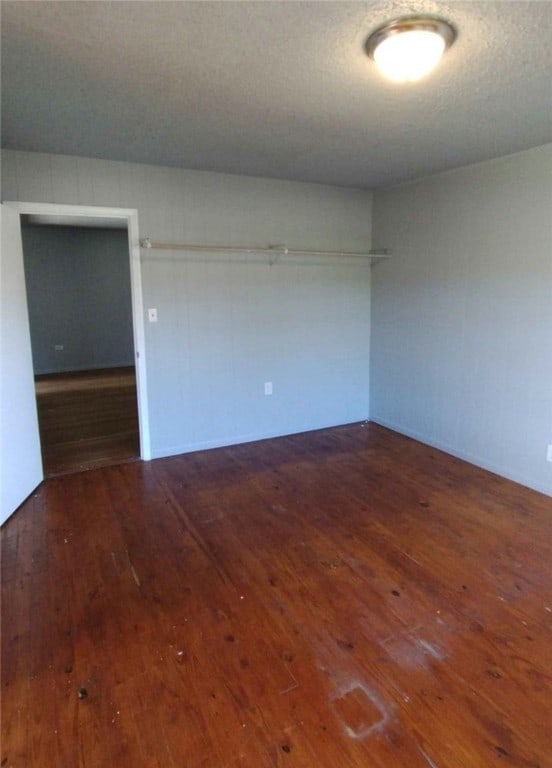 unfurnished room with a textured ceiling and dark hardwood / wood-style floors