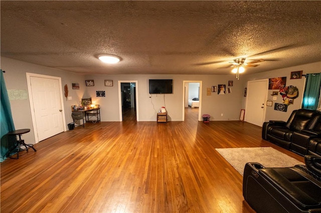 living area featuring a textured ceiling, ceiling fan, and wood finished floors