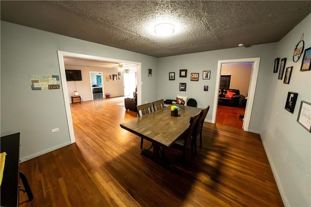 dining space with ceiling fan, a textured ceiling, baseboards, and wood finished floors