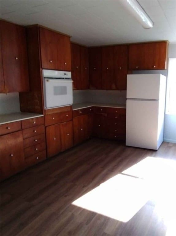 kitchen featuring white appliances and dark hardwood / wood-style floors