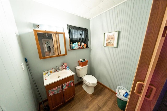 bathroom with toilet, baseboards, wood finished floors, and vanity