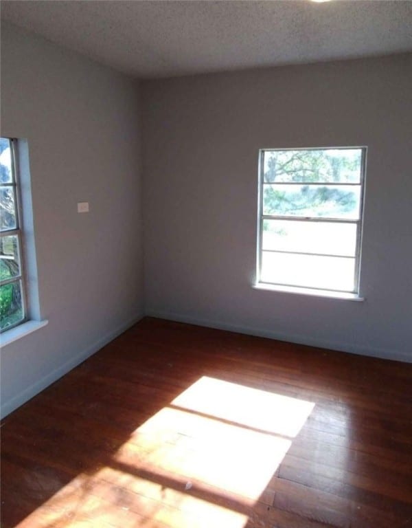 spare room featuring dark wood-type flooring and a textured ceiling