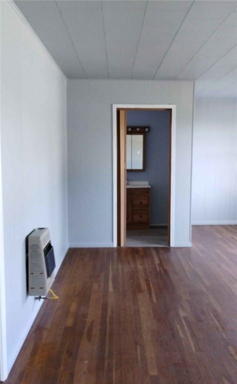 empty room featuring heating unit and dark hardwood / wood-style flooring