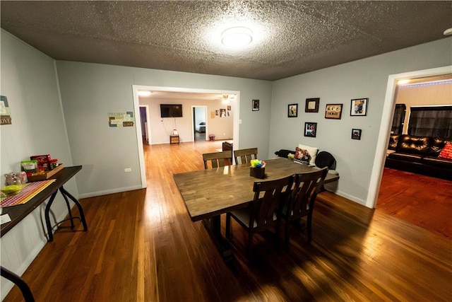 dining area with a textured ceiling, wood finished floors, and baseboards