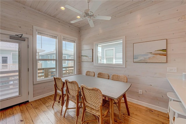 dining space featuring wood ceiling, wooden walls, light hardwood / wood-style floors, and a healthy amount of sunlight