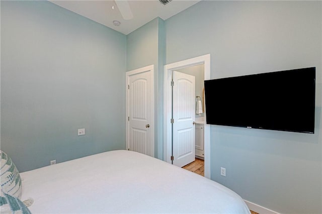 bedroom with connected bathroom and light hardwood / wood-style flooring