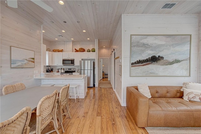 dining space featuring wood walls, wood ceiling, and light hardwood / wood-style flooring