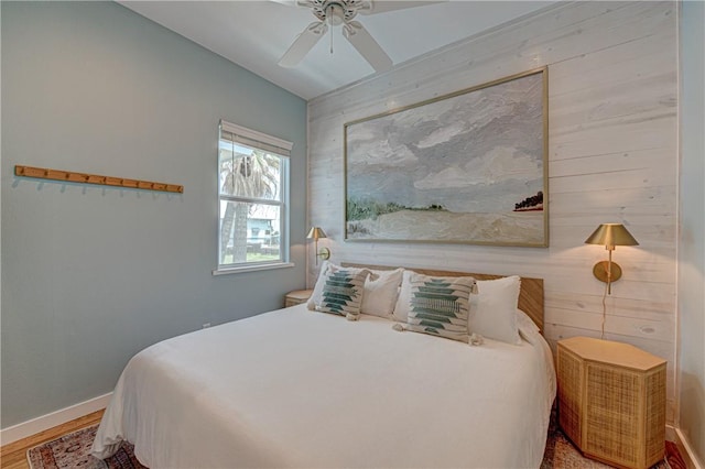 bedroom featuring ceiling fan, hardwood / wood-style floors, and wood walls