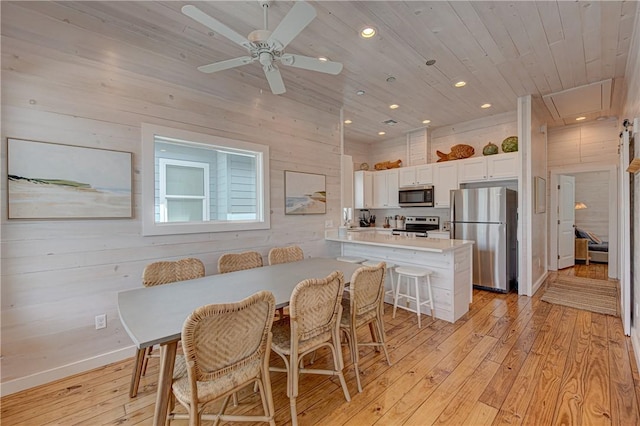 dining space featuring wood walls, light hardwood / wood-style floors, and wooden ceiling