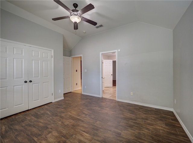 unfurnished bedroom with lofted ceiling, a closet, visible vents, wood finished floors, and baseboards