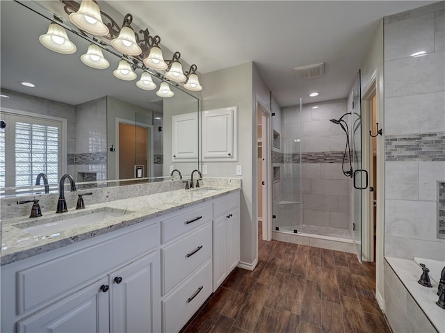 full bath with wood finished floors, a sink, visible vents, and a shower stall