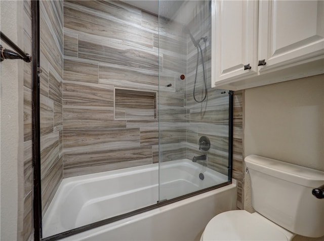 bathroom featuring toilet and bath / shower combo with glass door