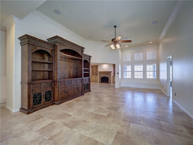 unfurnished living room with baseboards, a fireplace, a ceiling fan, and crown molding