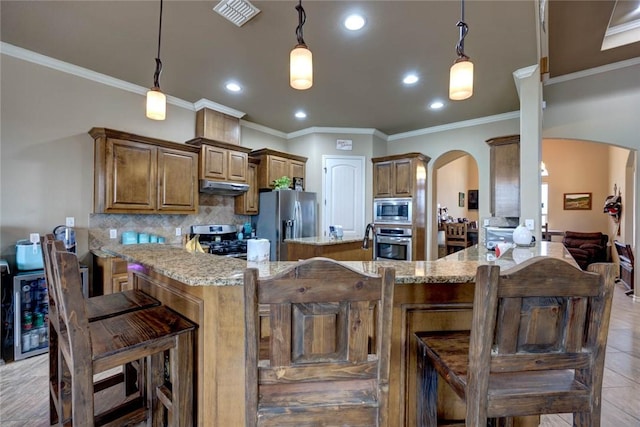 kitchen with light stone counters, hanging light fixtures, crown molding, and stainless steel appliances