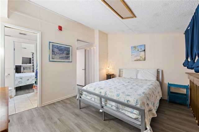 bedroom with hardwood / wood-style floors, a textured ceiling, and vaulted ceiling