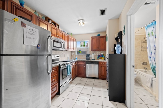 kitchen featuring decorative backsplash, light tile patterned floors, and appliances with stainless steel finishes