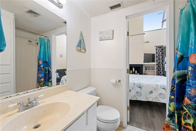 bathroom with vanity, a textured ceiling, hardwood / wood-style flooring, and toilet