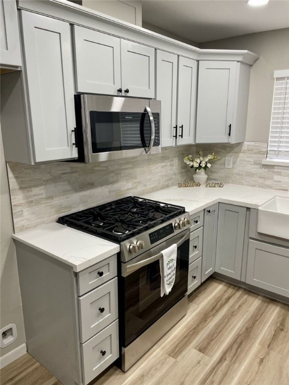 4917 Arlene Dr, Corpus Christi, TX 78411 - kitchen featuring appliances with stainless steel finishes, light wood-style flooring, tasteful backsplash, and light stone countertops