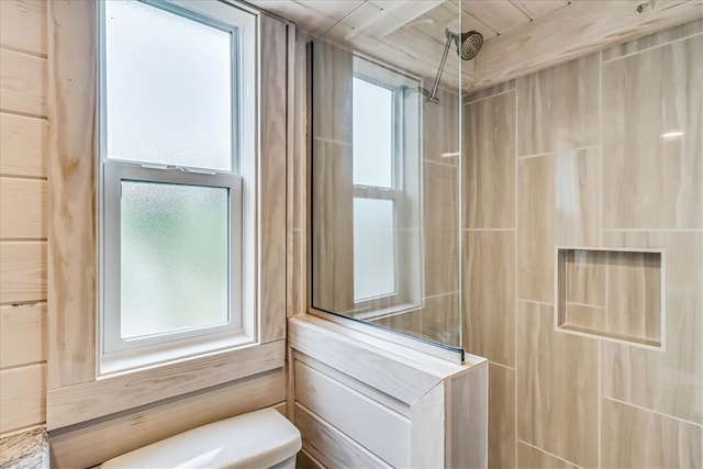 bathroom featuring a shower, wooden walls, and toilet