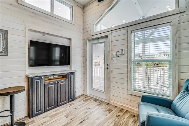 doorway to outside with wood walls, light hardwood / wood-style floors, and plenty of natural light