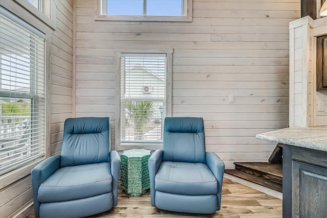 sitting room with light wood-type flooring and wooden walls