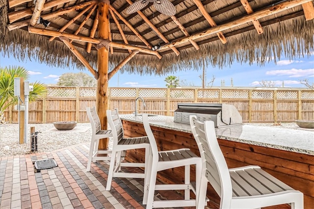 view of patio featuring ceiling fan, an outdoor wet bar, a gazebo, and exterior kitchen